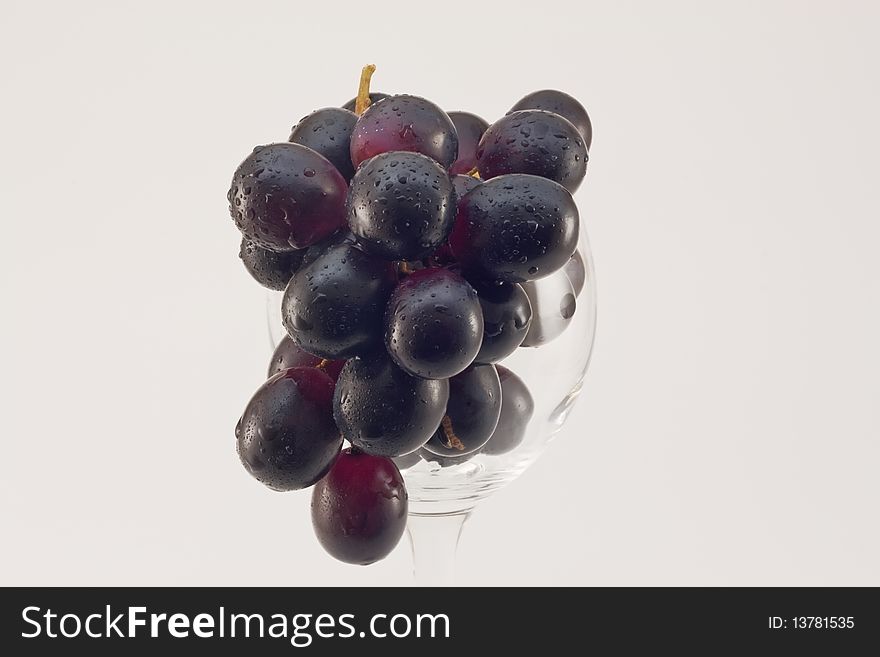 Grapes cluster in water drops in a glass on a white background