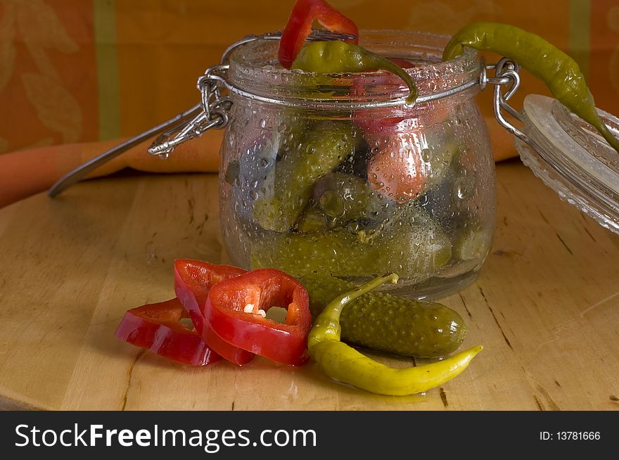 Pickles assortment in a glass jar, on light wood background. Pickles assortment in a glass jar, on light wood background