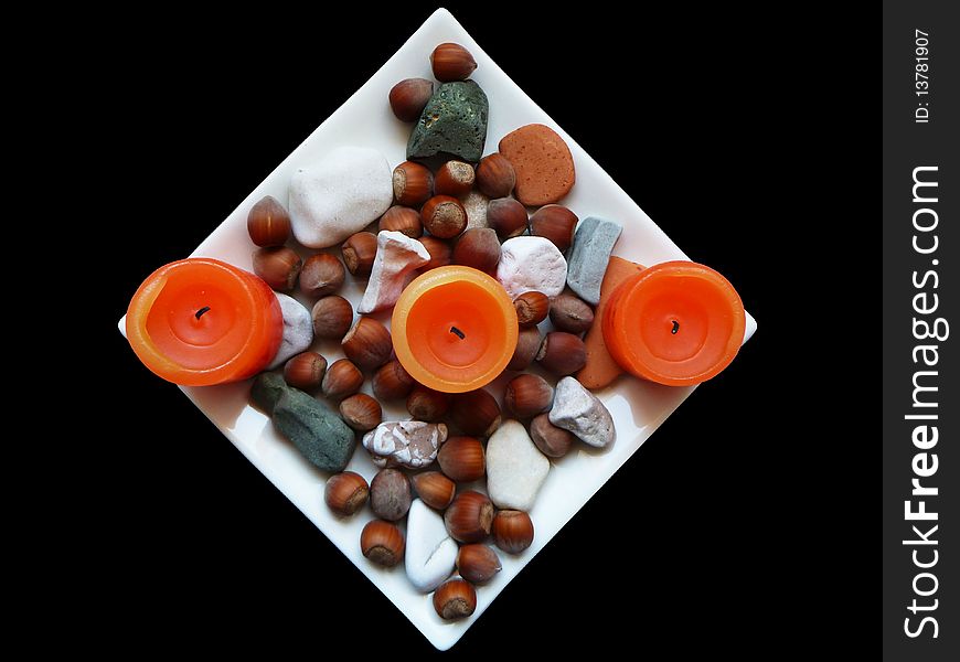 Candles on Plate accompanied with pebbles and nuts