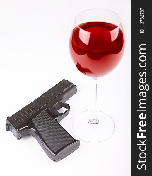 Closeup of pistol and glass of red wine isolated over white background. Closeup of pistol and glass of red wine isolated over white background