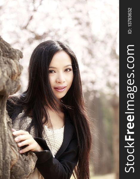 Beautiful Asian girl outdoors portrait spring. She is smiling under the oriental cherry tree. Beautiful Asian girl outdoors portrait spring. She is smiling under the oriental cherry tree.