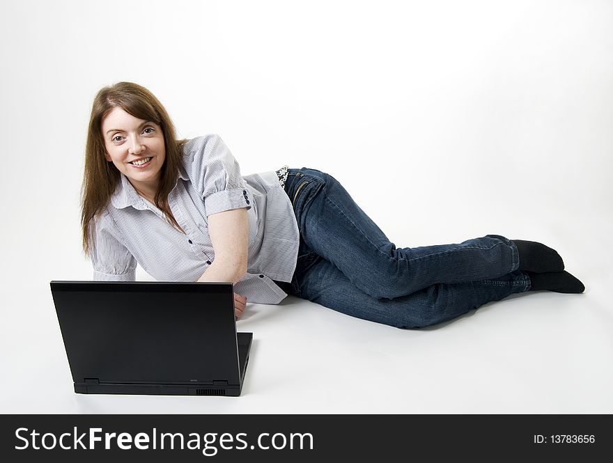 A horizontal image of a pretty young female lying on the floor with her laptop. A horizontal image of a pretty young female lying on the floor with her laptop