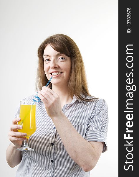 A vertical image of a pretty young woman with a glass of orange juice in her hand and sipping from a blue straw