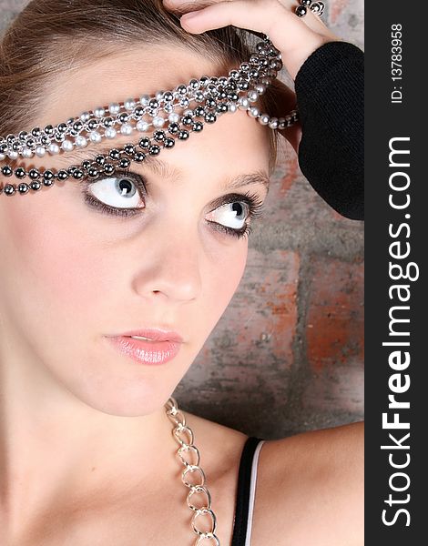 Young female model with silver jewellery against a brick wall background. Young female model with silver jewellery against a brick wall background