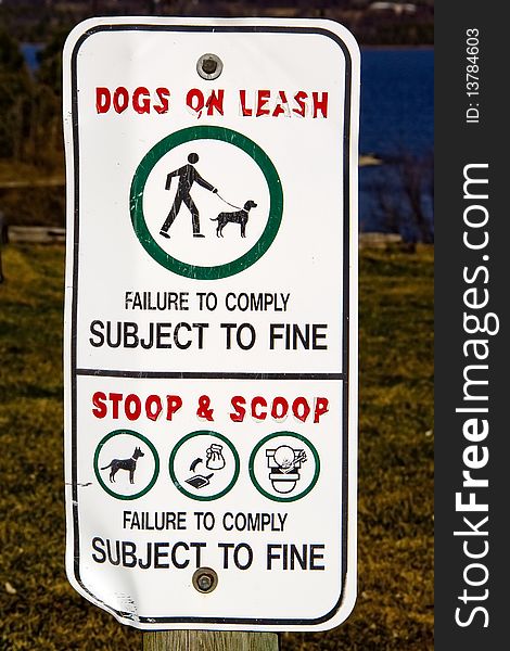 A sign warning to keep dogs on a leash and owners to clean up their dog's messes, or face a fine. A sign warning to keep dogs on a leash and owners to clean up their dog's messes, or face a fine.