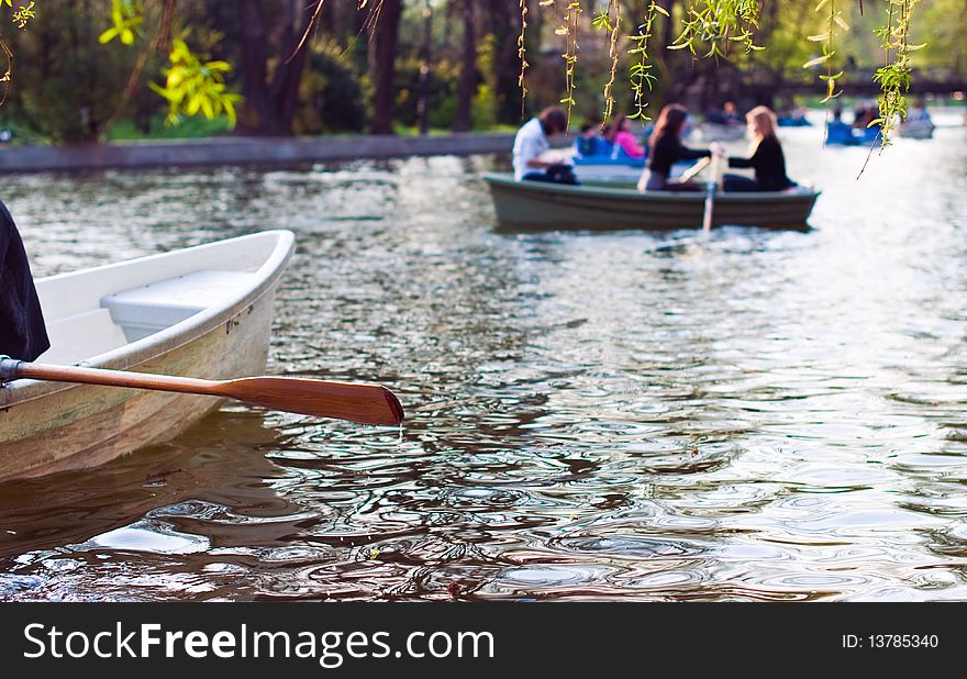 Boats on the river in a park with happy people enjoying a summer day