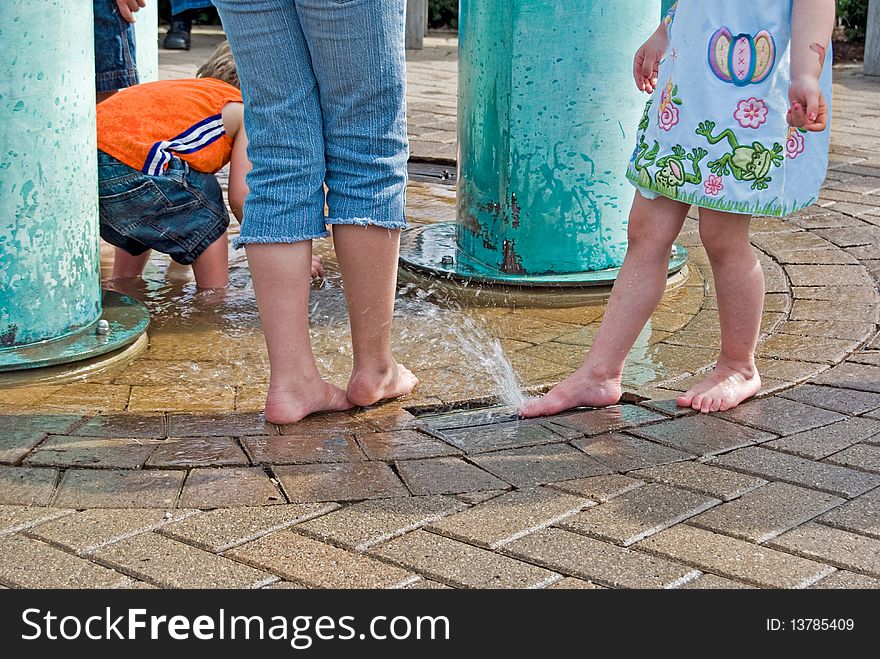 Kids with adult playing in a park fountain. Kids with adult playing in a park fountain.