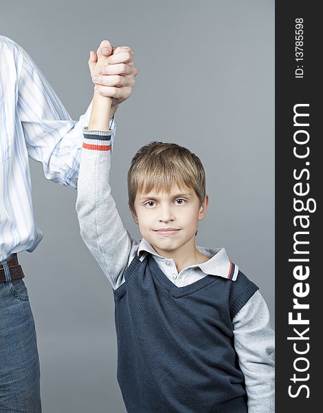 Young teenager boy with father near standing with happy facial expression and making winning sign with hand isolated over gray background. Young teenager boy with father near standing with happy facial expression and making winning sign with hand isolated over gray background