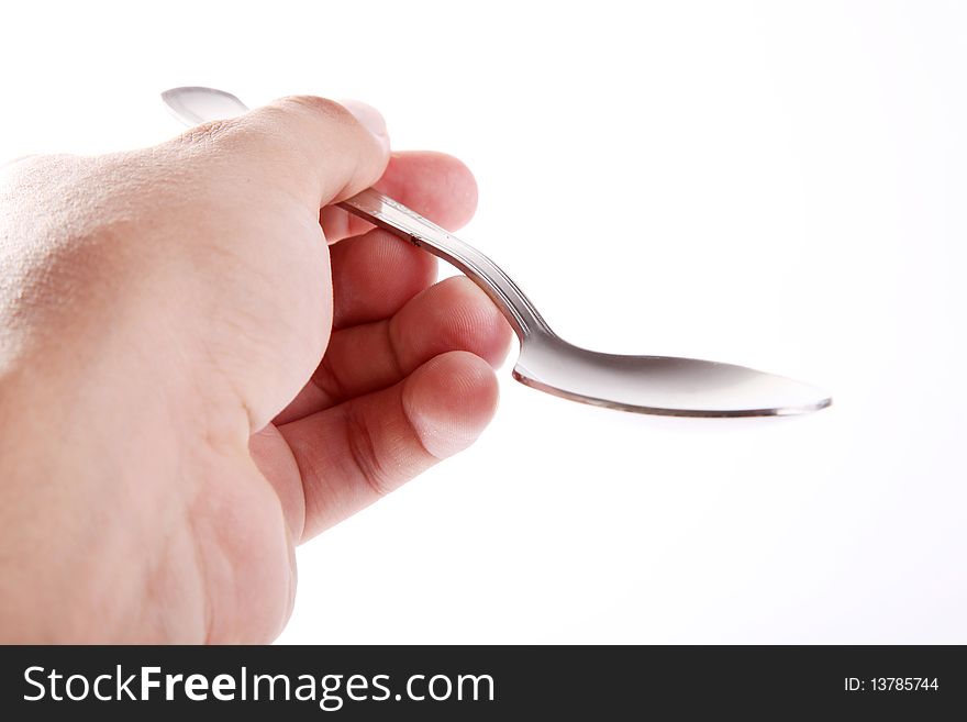A man's hand holding an empty silver spoon on white background