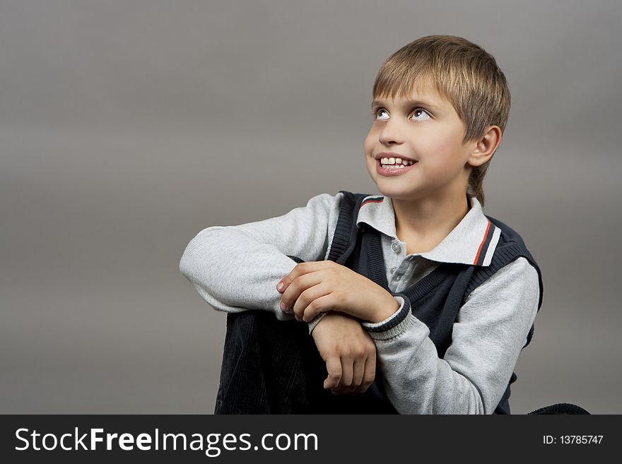 Smiling young caucasian teenager boy with calm face expression and looking up isolated over gray background. Smiling young caucasian teenager boy with calm face expression and looking up isolated over gray background