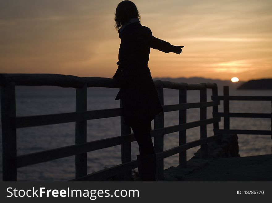 Woman standing at the sea in the sunset. Woman standing at the sea in the sunset