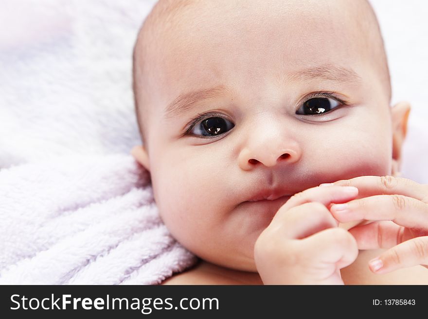 Beauty baby looking at camera on white blanket