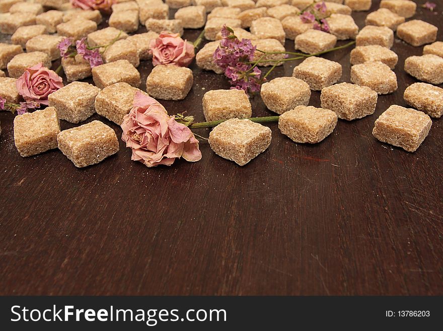 Cane sugar and flowers on a grunge brown wooden table
