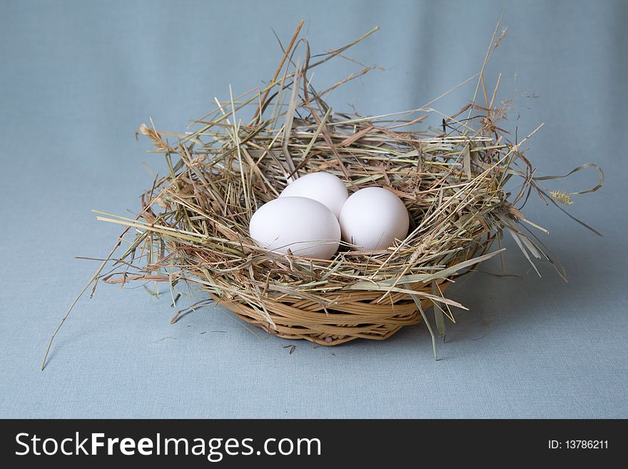 Three eggs lies in basket at hay