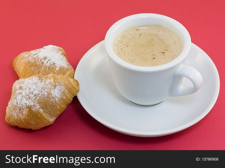 Cup of coffee on a saucer with two croissants on a red background. Cup of coffee on a saucer with two croissants on a red background