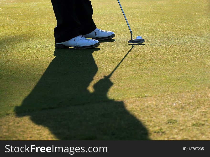 A golfer is about to putt the ball into the hole. A golfer is about to putt the ball into the hole.
