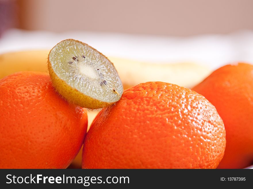 Green kiwi above orange on the table