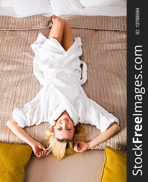 Woman Lying On Bed Dressed In  White Robe