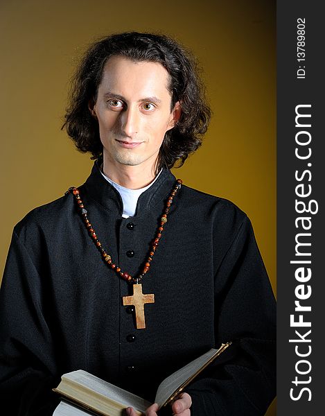 Conceptual portrait of Praying priest with wooden cross reading Holy Bible. yellow background. Conceptual portrait of Praying priest with wooden cross reading Holy Bible. yellow background