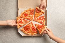Young People Taking Slices Of Hot Cheese Pizza From Cardboard Box At Table, Top View. Food Delivery Stock Image