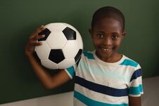 Front View Of Black Schoolboy Holding Football And Looking At Camera In Classroom Royalty Free Stock Images