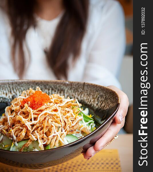 Woman holding a bowl of crispy fried shredded chiken salad, Japanese style salad with vegetables and shrimp roe on top. Woman holding a bowl of crispy fried shredded chiken salad, Japanese style salad with vegetables and shrimp roe on top