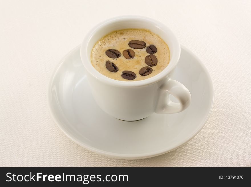 Cup of cappuccino with coffee grains on a white linen cloth