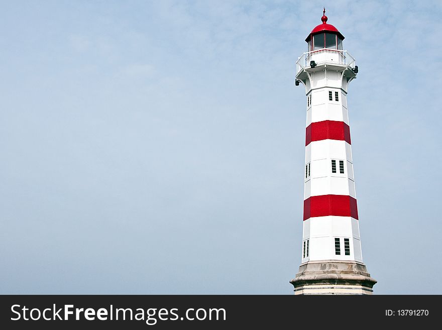 A lighthouse in red and white on a slightly overcast sky. A lighthouse in red and white on a slightly overcast sky.