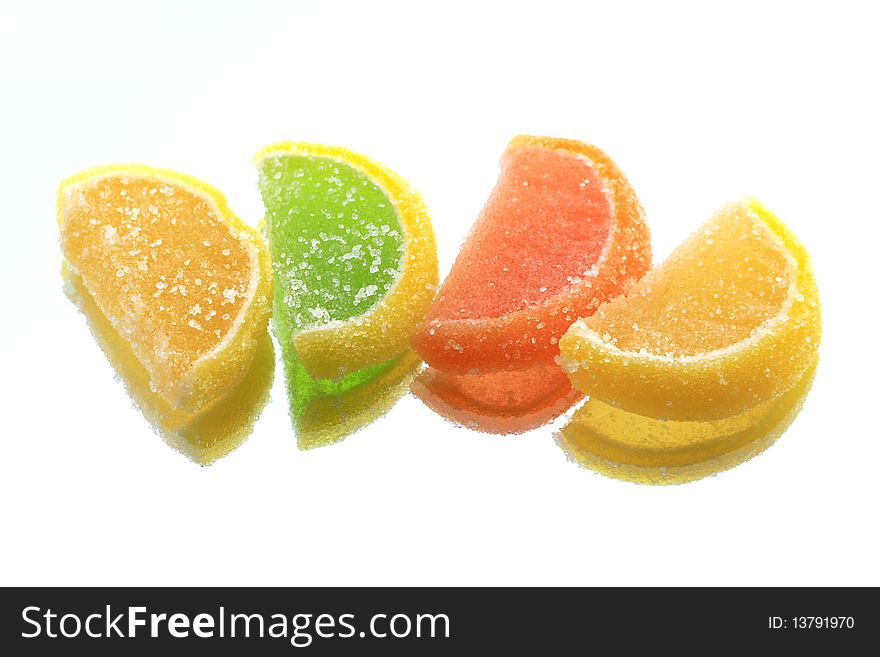 Few colored fruit jelly lying in a row on glass background with reverberation