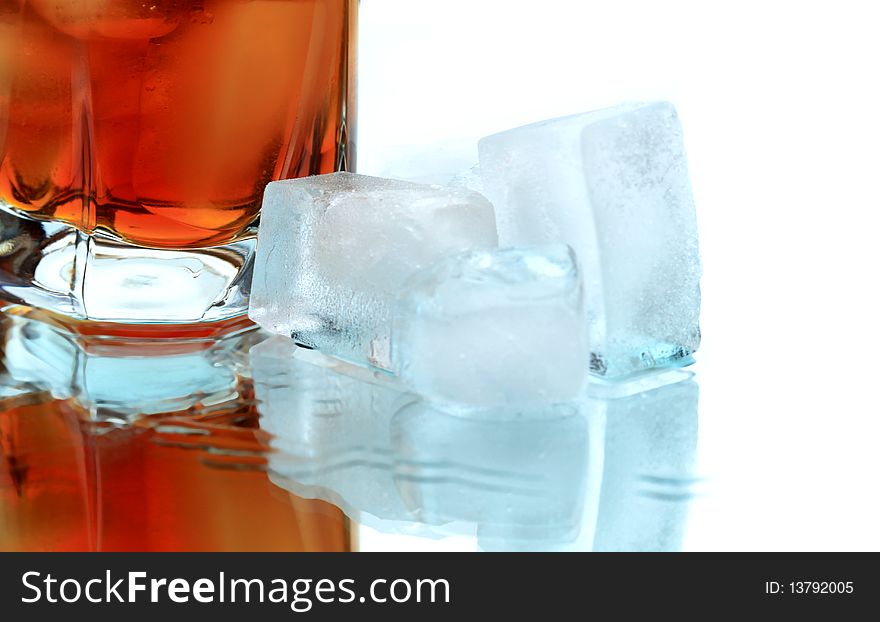 Glass of whiskey with ice cubes on white background with reverberation