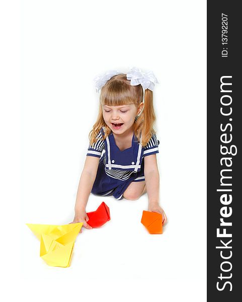 Cute young girl in sailor dress with paper ships over white. Cute young girl in sailor dress with paper ships over white