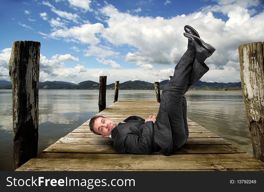 Businessman lying upright on a dock. Businessman lying upright on a dock