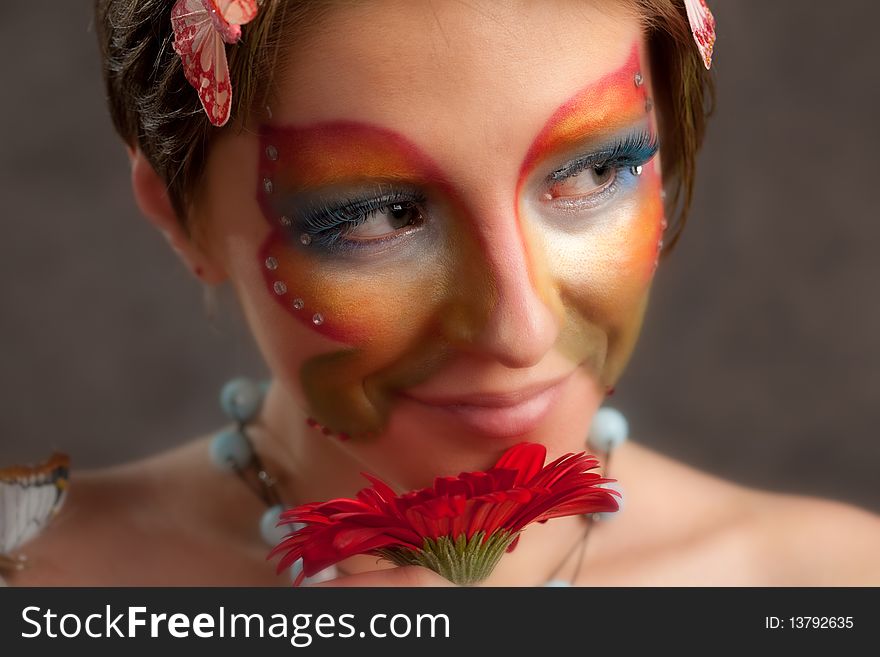 Girl with butterfly make-up on face and flower look right. Girl with butterfly make-up on face and flower look right