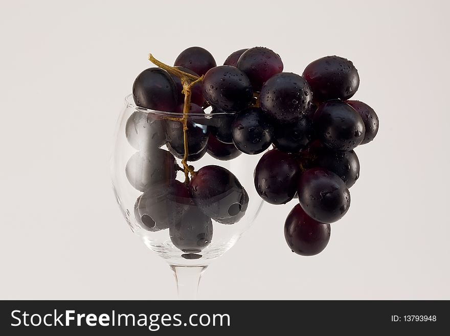 Grapes cluster in water drops in a glass on a white background