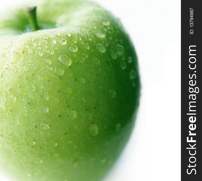 Green apple with drops of water on a white background