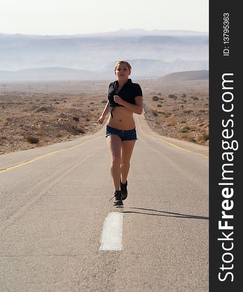 Young girl running over a desert highway. Young girl running over a desert highway.