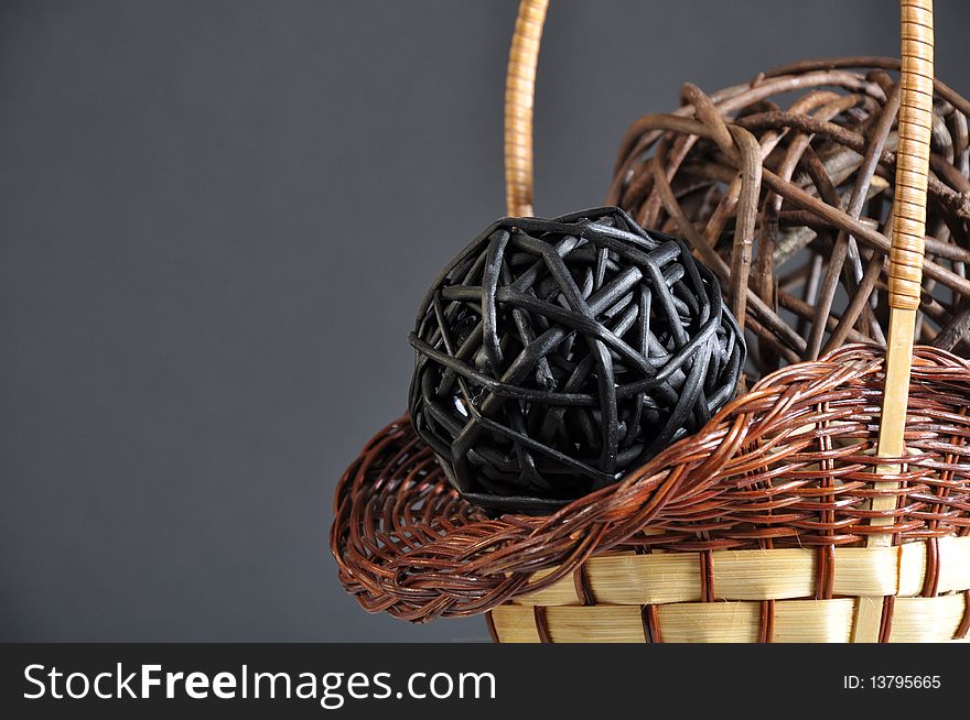 Studio photo containing a wicker handmade basket, wicker spheres, arranged so their outline matches one of the photo's diagonals. Studio photo containing a wicker handmade basket, wicker spheres, arranged so their outline matches one of the photo's diagonals