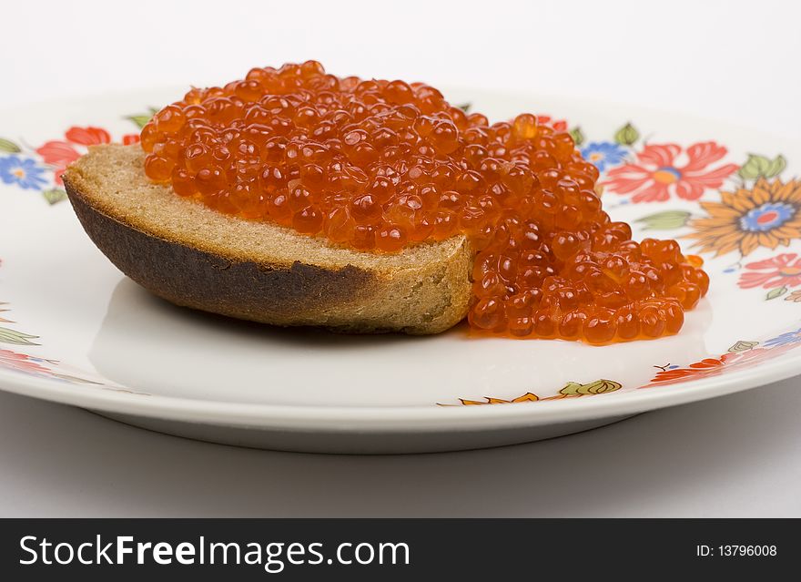Red caviar on a piece of black bread on a white background