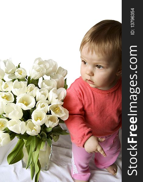 The child with white tulips looks aside and shows an index finger. The child with white tulips looks aside and shows an index finger