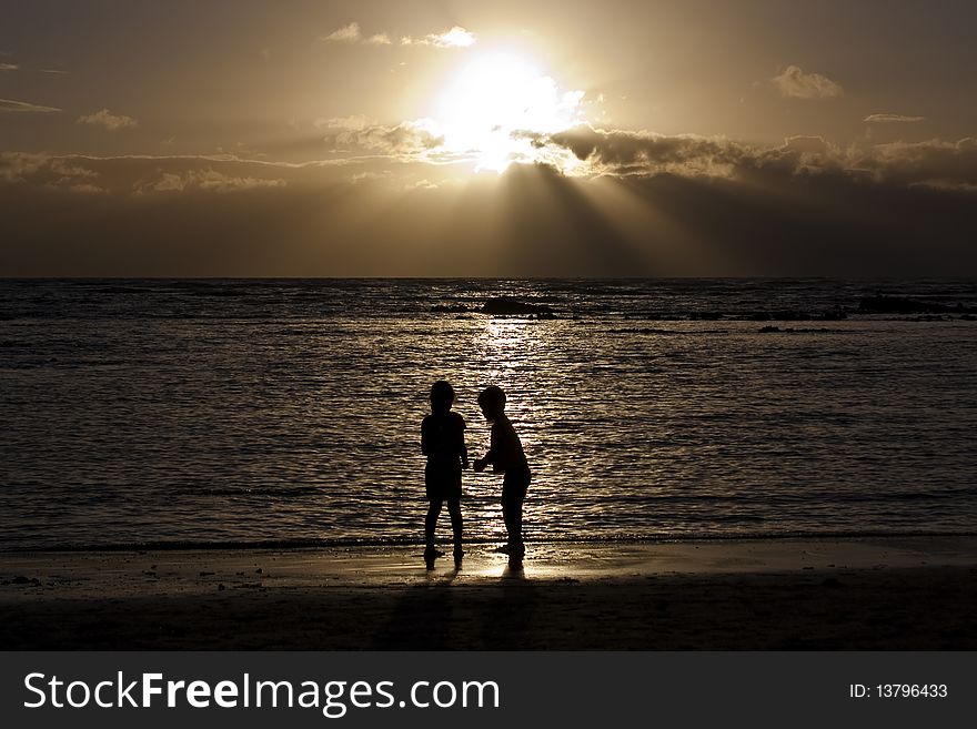 Two children on the beach at sunset