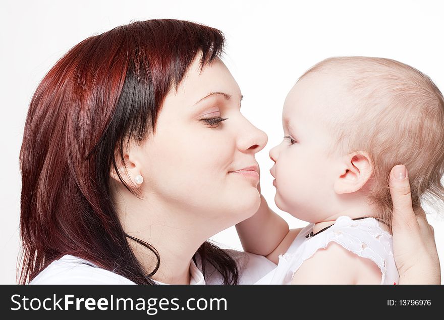 Cute baby trying to kiss her mother. Closeup portrait.