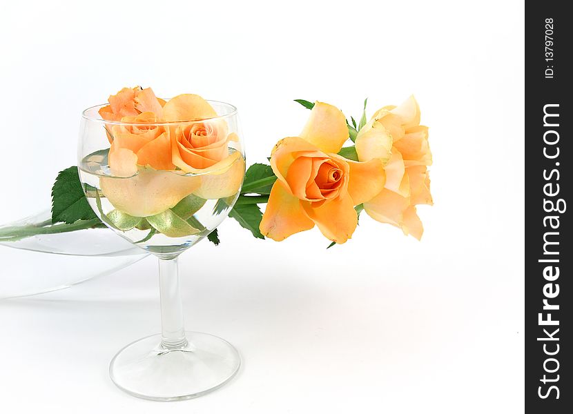 Yellow rose in a glass vase and wineglass with a yellow bud rose on a white background. Yellow rose in a glass vase and wineglass with a yellow bud rose on a white background