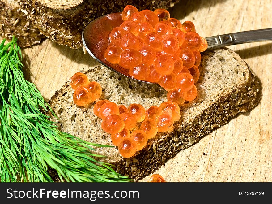 Red caviar in a spoon on a slice of rye bread. Red caviar in a spoon on a slice of rye bread