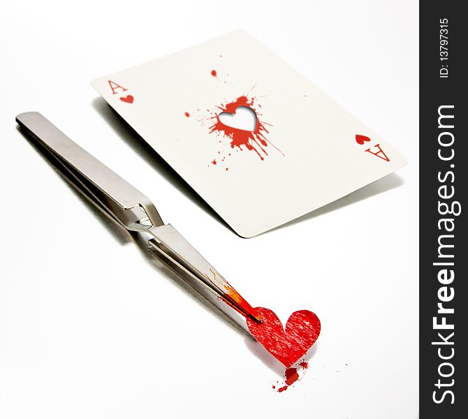 Some tweezers holding a paper heart, just removed from an ace of hearts. Some tweezers holding a paper heart, just removed from an ace of hearts.