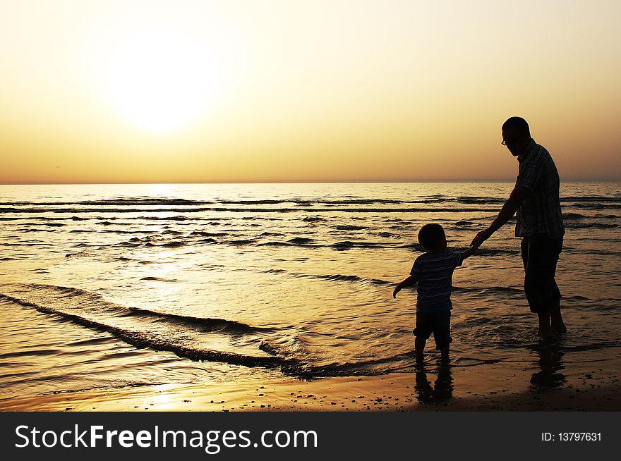 Child with his father at sea. Sunset