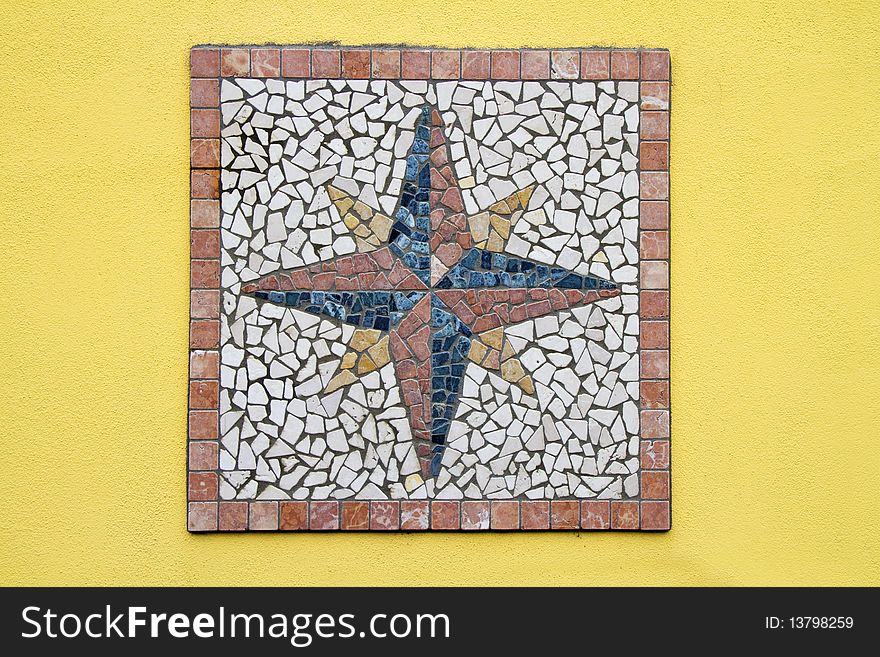 Mosaic compass rose on a yellow wall