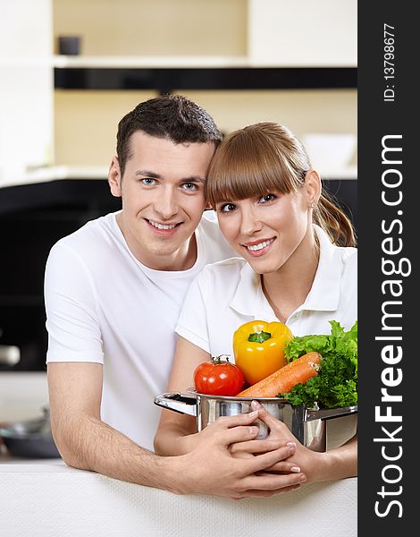 Young couple with capacity with vegetables in the foreground. Young couple with capacity with vegetables in the foreground