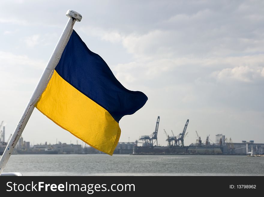 Waving blue and yellow flag on the background of the port