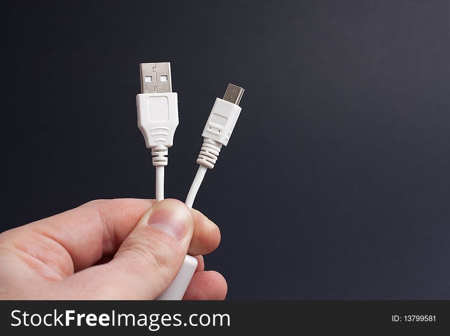 A hand holding an USB-to-miniUSB cable. A hand holding an USB-to-miniUSB cable.