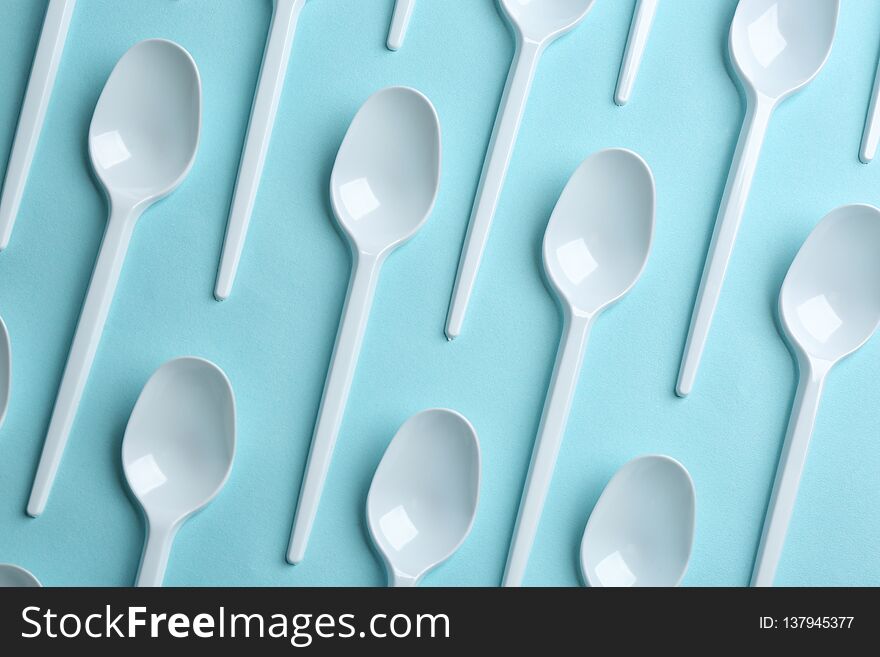 Flat lay composition with plastic spoons on color background